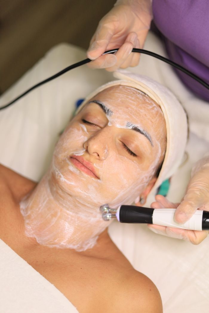 hero-img-01 Client receiving advanced skincare treatment with facial toning device in a clinic.